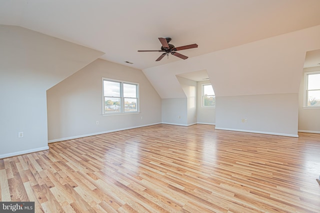 additional living space featuring light wood-type flooring, vaulted ceiling, and a wealth of natural light