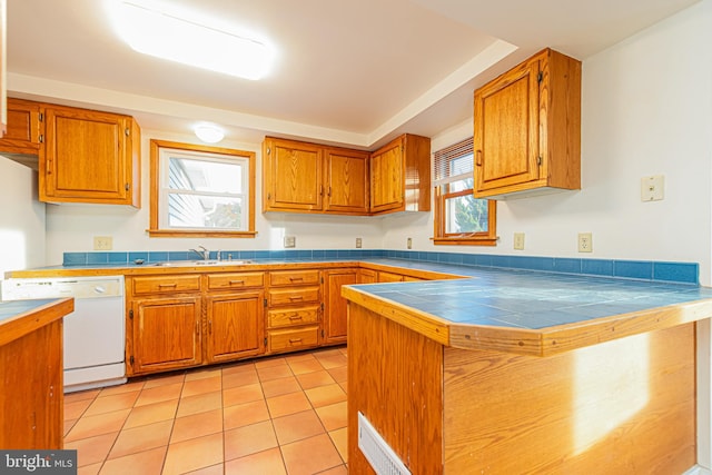 kitchen featuring tile counters, dishwasher, light tile patterned floors, and a wealth of natural light