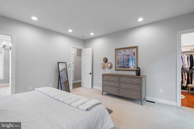 bedroom featuring light colored carpet, a spacious closet, and a closet