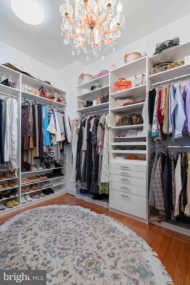 walk in closet featuring an inviting chandelier and light hardwood / wood-style flooring