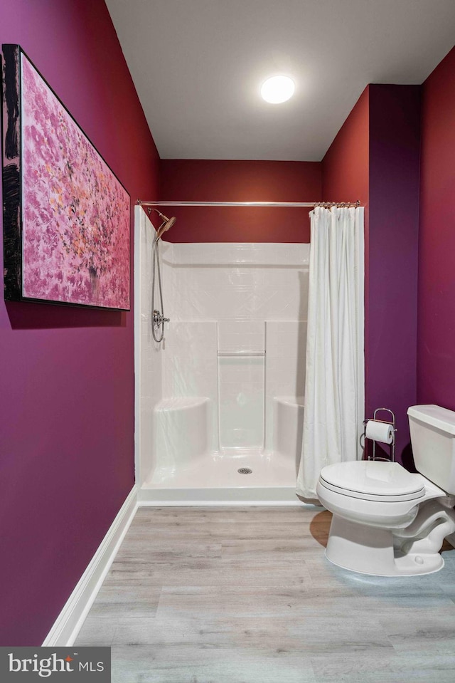 bathroom featuring toilet, wood-type flooring, and walk in shower