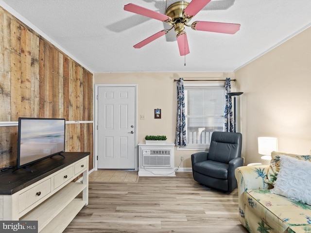 living room featuring a textured ceiling, light hardwood / wood-style floors, a wall unit AC, and wooden walls