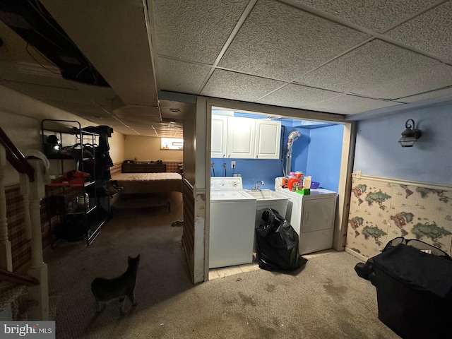 basement with washer and dryer, a paneled ceiling, and light carpet