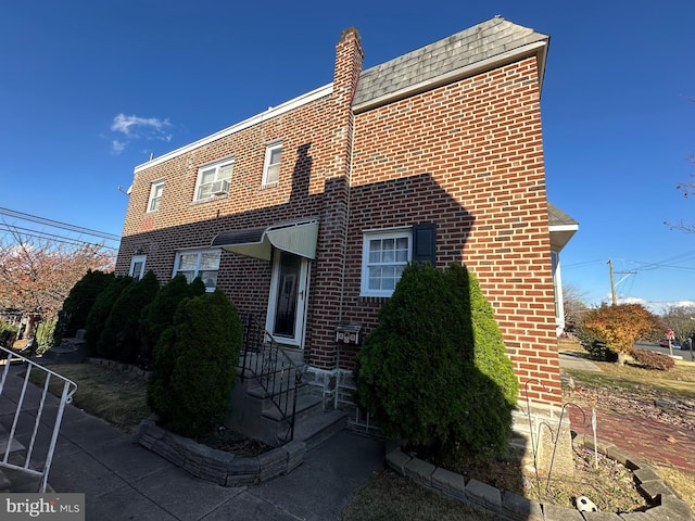 view of home's exterior with a shingled roof and brick siding