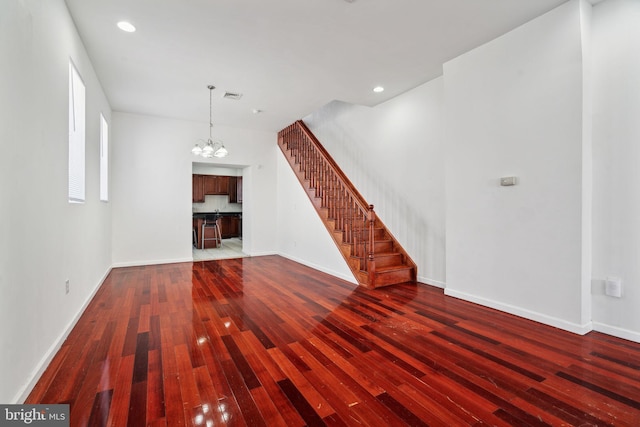 unfurnished living room with wood-type flooring and a notable chandelier