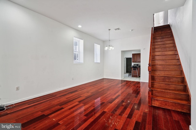 unfurnished living room with hardwood / wood-style floors and an inviting chandelier