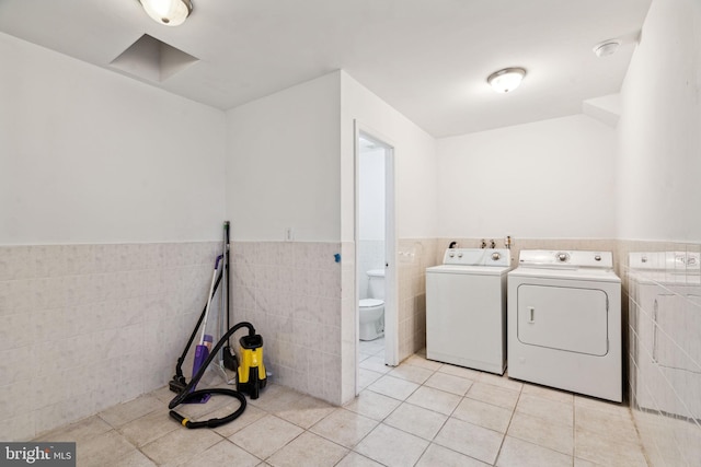 clothes washing area featuring washing machine and dryer, tile walls, and light tile patterned floors