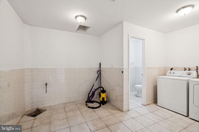 laundry room with washer and clothes dryer, light tile patterned floors, and tile walls