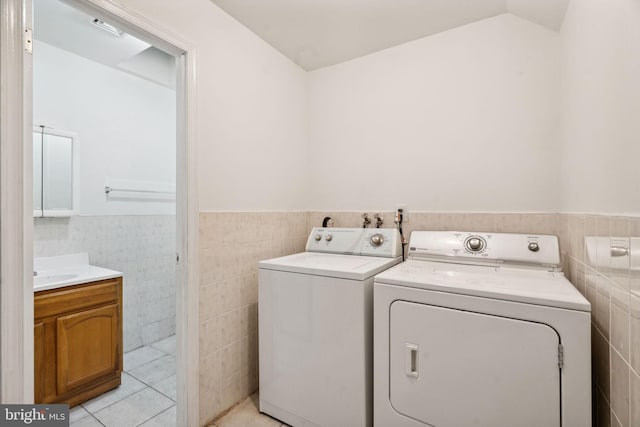 washroom with sink, tile walls, light tile patterned flooring, and washer and dryer