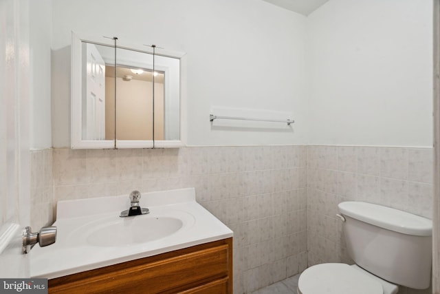 bathroom with vanity, toilet, and tile walls