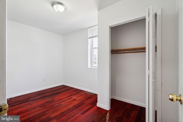 unfurnished bedroom featuring a closet and dark wood-type flooring