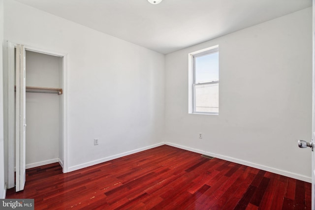 unfurnished bedroom featuring dark hardwood / wood-style floors and a closet