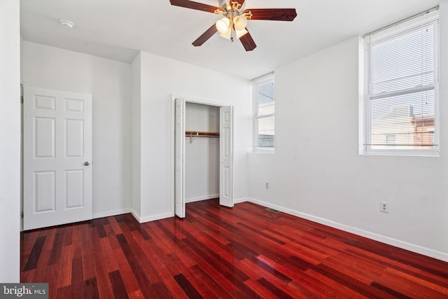 unfurnished bedroom featuring dark hardwood / wood-style floors, multiple windows, and ceiling fan