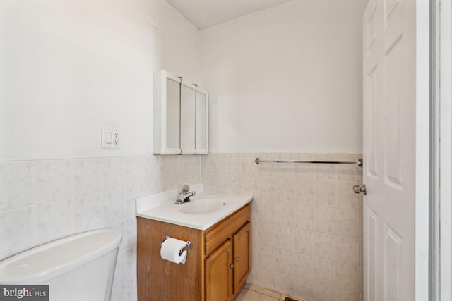 bathroom featuring tile patterned flooring, vanity, tile walls, and toilet