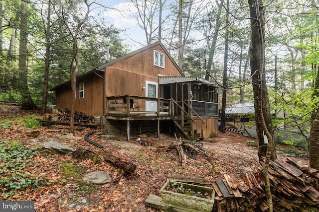 rear view of property featuring a sunroom, a wooden deck, and stairs