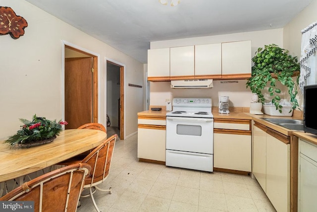 kitchen featuring white range with electric cooktop, light countertops, ventilation hood, white cabinets, and a sink