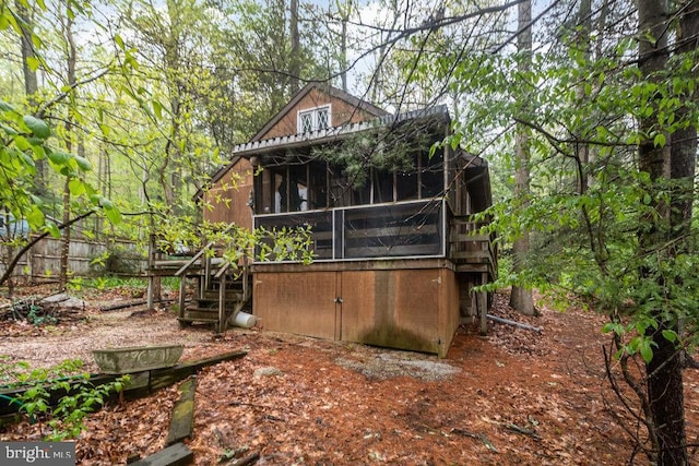 rear view of property with a sunroom and stairs