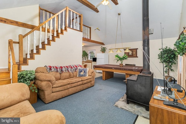 carpeted living room featuring a wood stove, stairway, ceiling fan, high vaulted ceiling, and beam ceiling