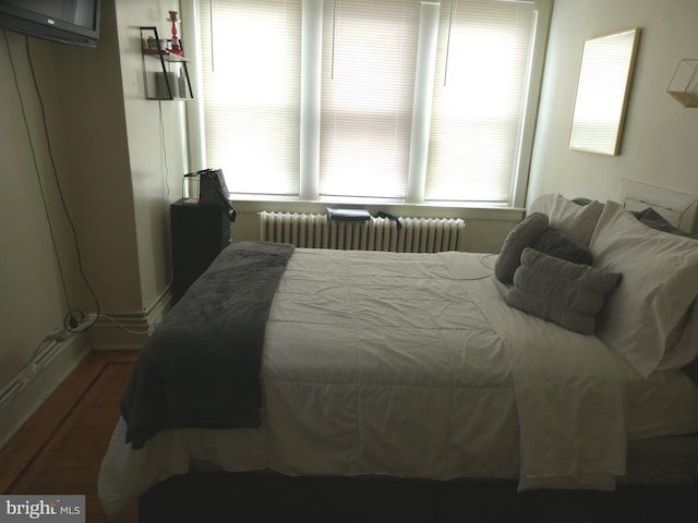 bedroom featuring radiator heating unit and dark wood-type flooring