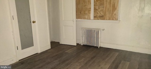 unfurnished room with dark hardwood / wood-style flooring and radiator heating unit