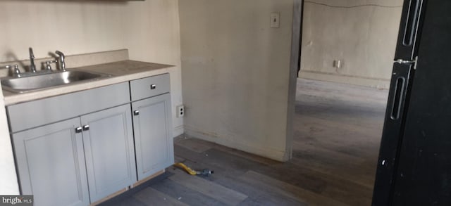 kitchen with black fridge, sink, white cabinets, and dark wood-type flooring