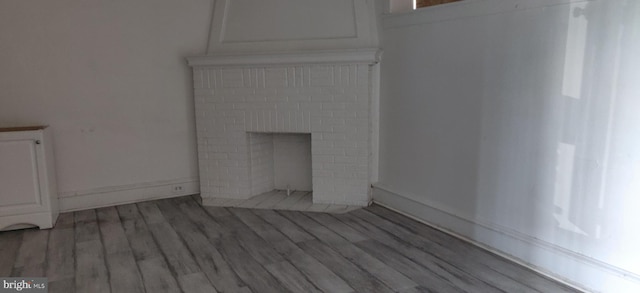 unfurnished living room with hardwood / wood-style floors and a brick fireplace