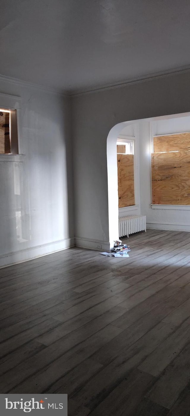 unfurnished room with radiator, crown molding, and hardwood / wood-style floors