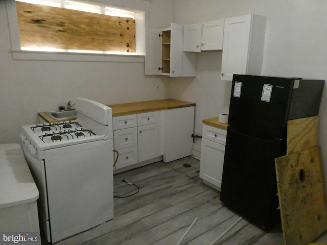 kitchen featuring butcher block counters, white cabinetry, black refrigerator, and white range with gas stovetop