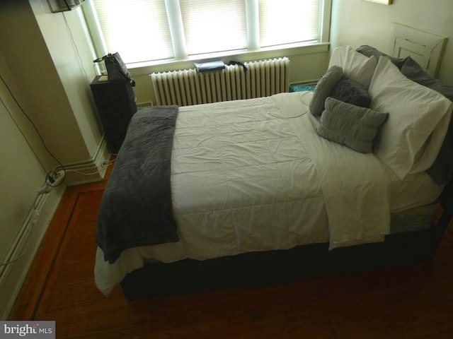 bedroom with dark hardwood / wood-style flooring and radiator heating unit