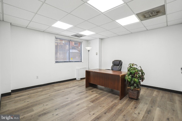 office area featuring a paneled ceiling and hardwood / wood-style flooring