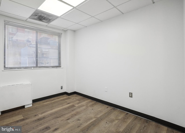 spare room featuring a drop ceiling and hardwood / wood-style flooring