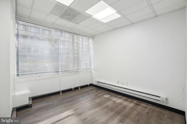 unfurnished room with hardwood / wood-style floors, a paneled ceiling, and a baseboard heating unit