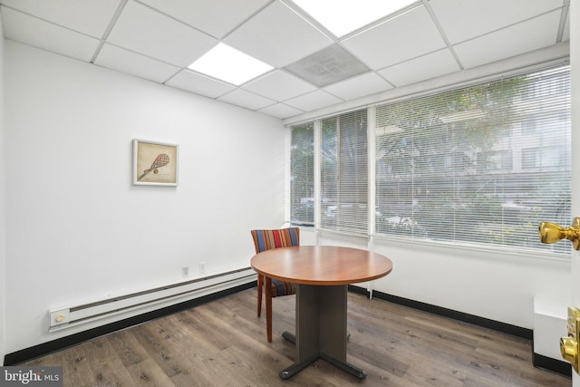 office with hardwood / wood-style floors, a drop ceiling, and a baseboard heating unit