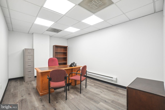 office space with a baseboard radiator, light hardwood / wood-style flooring, and a drop ceiling