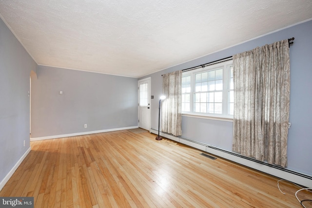 spare room with light wood-type flooring, a textured ceiling, and a baseboard radiator