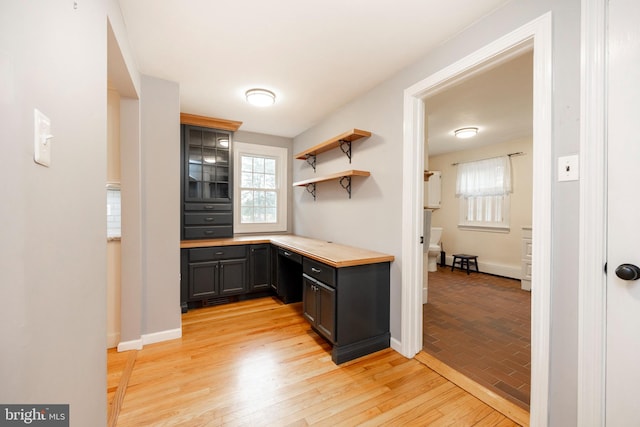 kitchen featuring butcher block counters, backsplash, gray cabinets, built in desk, and light wood-type flooring