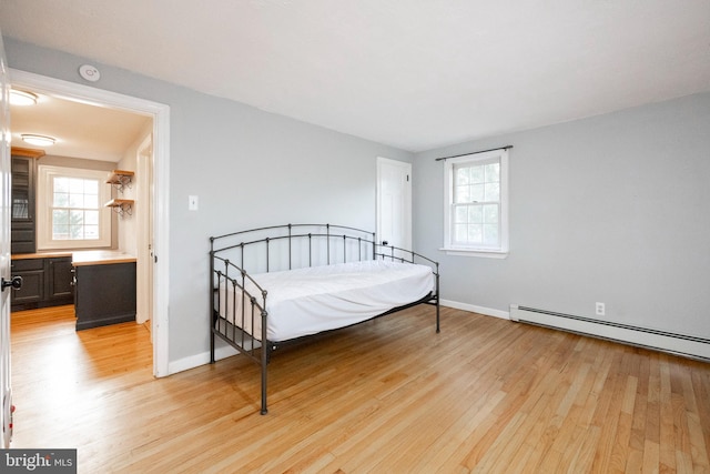 bedroom with light wood-type flooring and baseboard heating