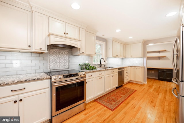 kitchen featuring custom exhaust hood, sink, tasteful backsplash, light hardwood / wood-style floors, and stainless steel appliances