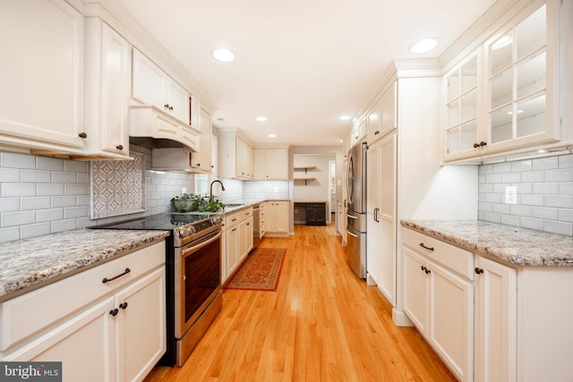 kitchen with custom exhaust hood, tasteful backsplash, light hardwood / wood-style floors, light stone counters, and stainless steel appliances