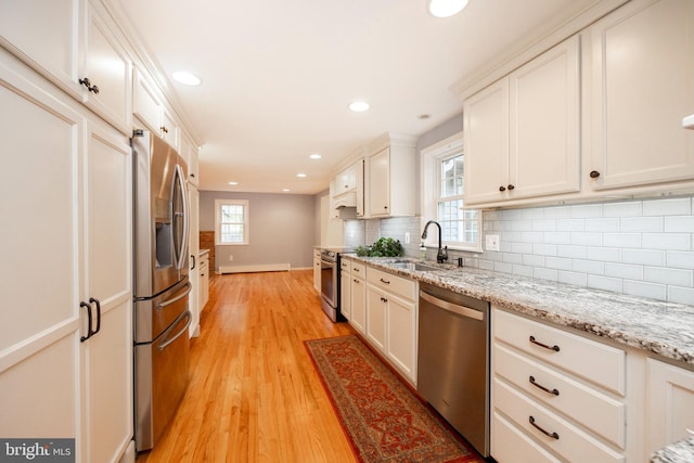 kitchen with appliances with stainless steel finishes, light wood-type flooring, a healthy amount of sunlight, and sink