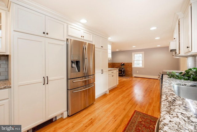 kitchen with white cabinets, stainless steel fridge, and tasteful backsplash