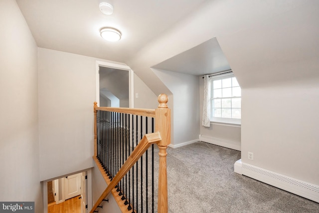 corridor with light colored carpet, a baseboard radiator, and vaulted ceiling