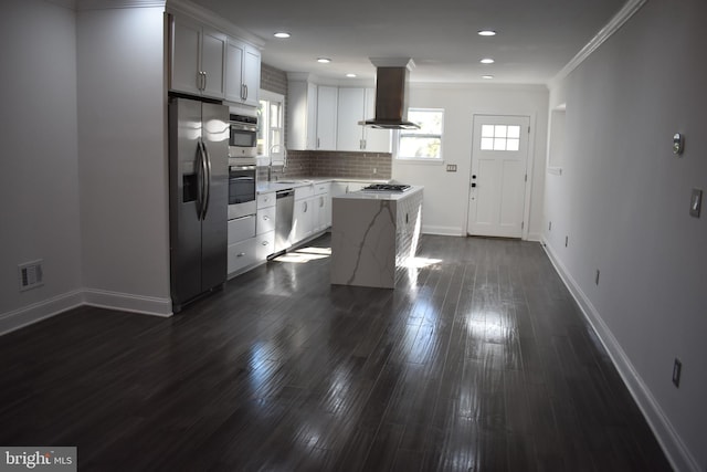 kitchen with dark wood-type flooring, appliances with stainless steel finishes, range hood, a kitchen island, and white cabinetry