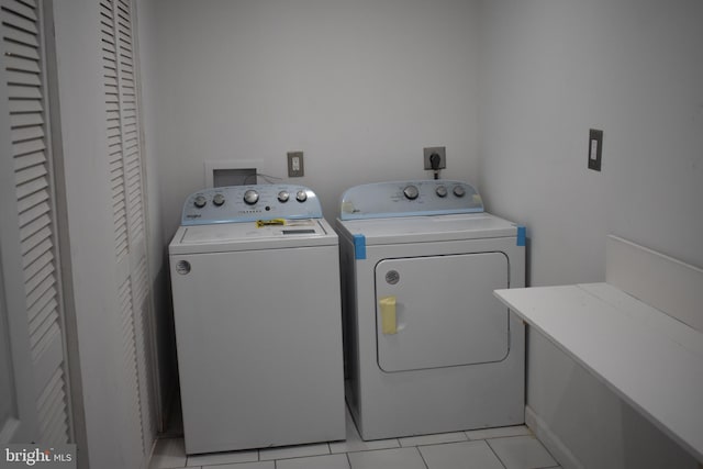 clothes washing area with independent washer and dryer and light tile patterned floors