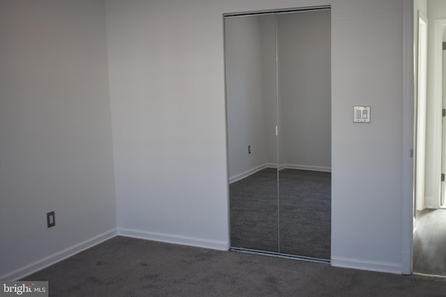 unfurnished bedroom featuring dark colored carpet and a closet