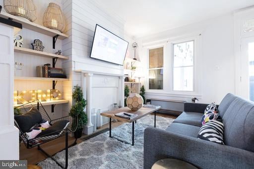 living room with a fireplace, hardwood / wood-style flooring, and wood walls