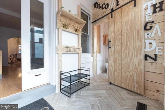 corridor with a barn door, wood walls, and light parquet flooring