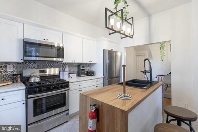 kitchen with white cabinetry, a center island, sink, stainless steel appliances, and backsplash