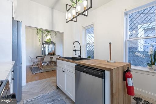 kitchen featuring white cabinetry, sink, hanging light fixtures, a chandelier, and stainless steel appliances