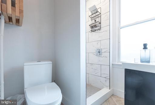 bathroom with a shower, plenty of natural light, and toilet